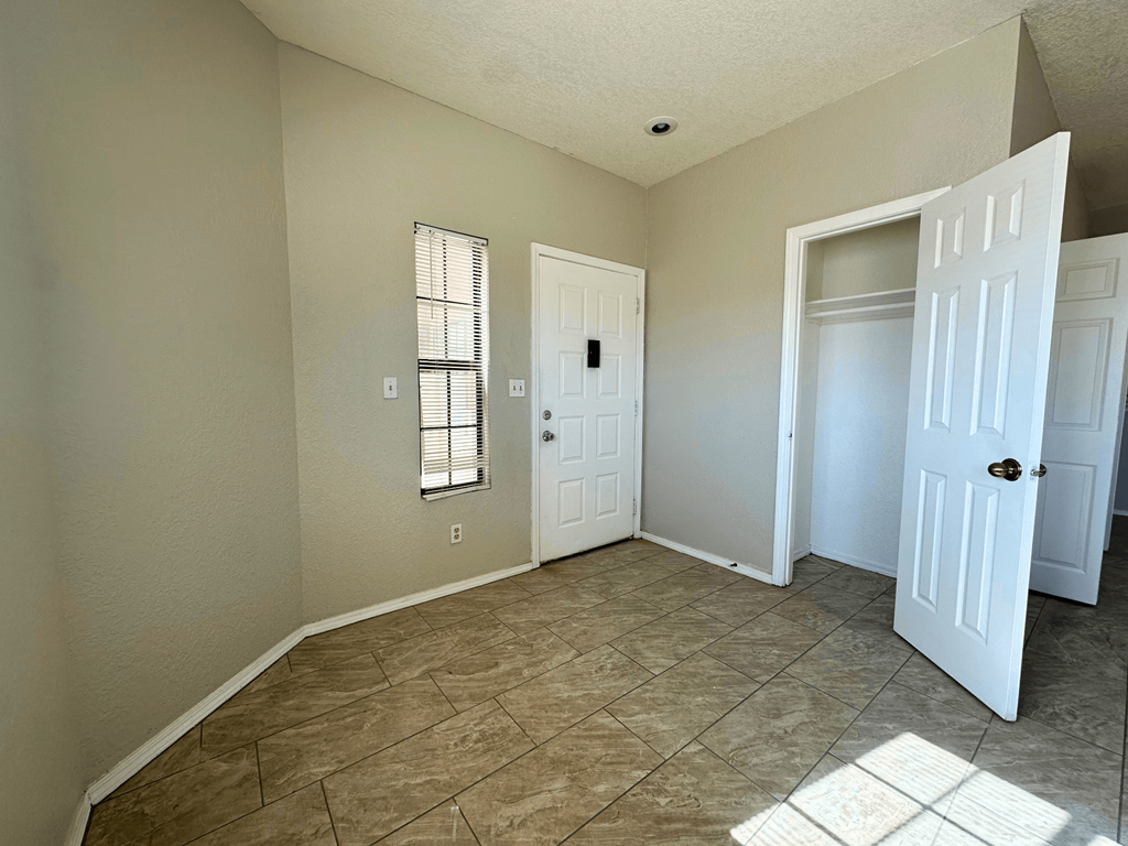 A room with a white door and a window with blinds.