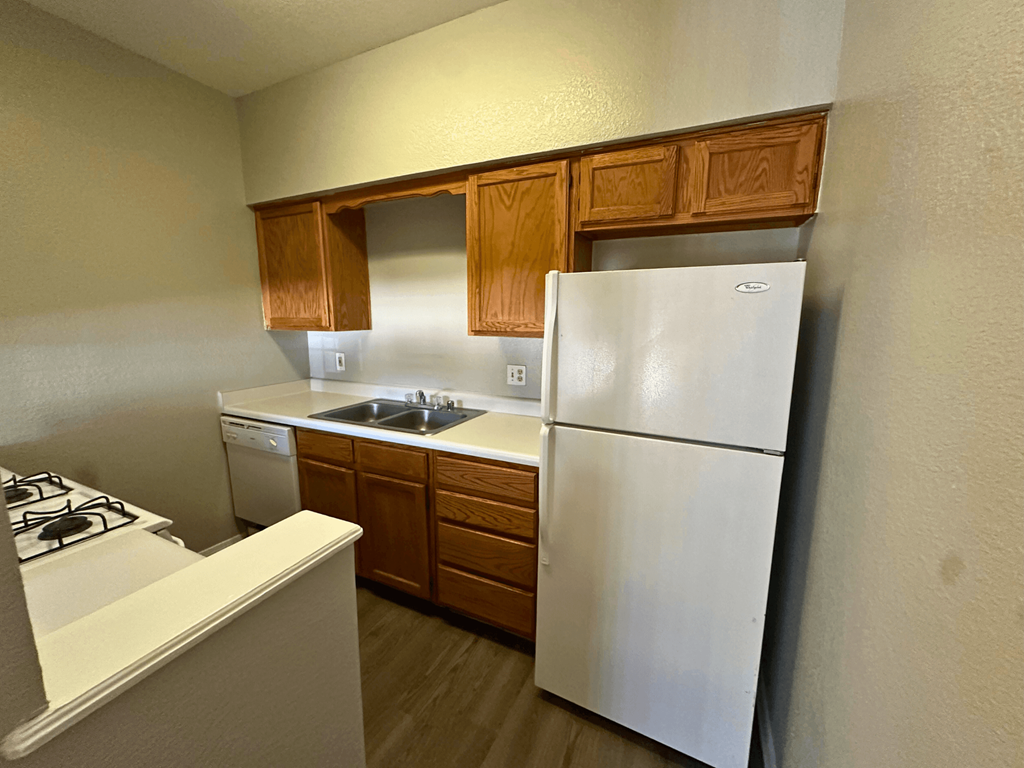 A white refrigerator is in a kitchen with wooden cabinets.
