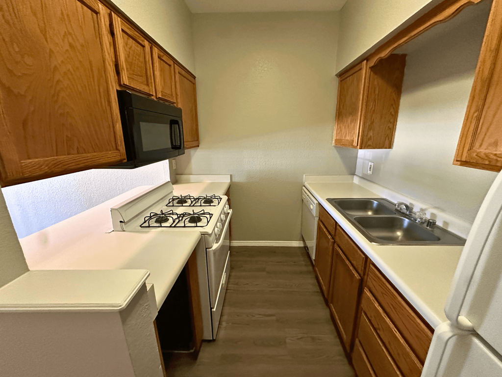 A kitchen with a white stove top oven and a white refrigerator.