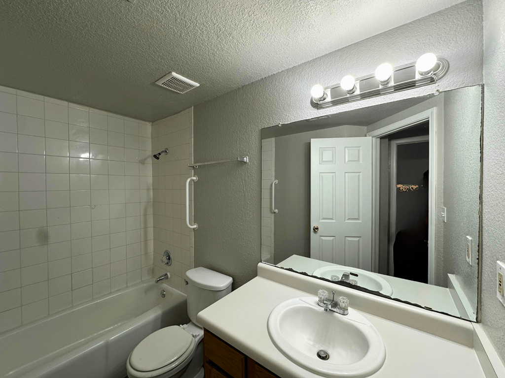 A white bathroom with a toilet, sink, and mirror.