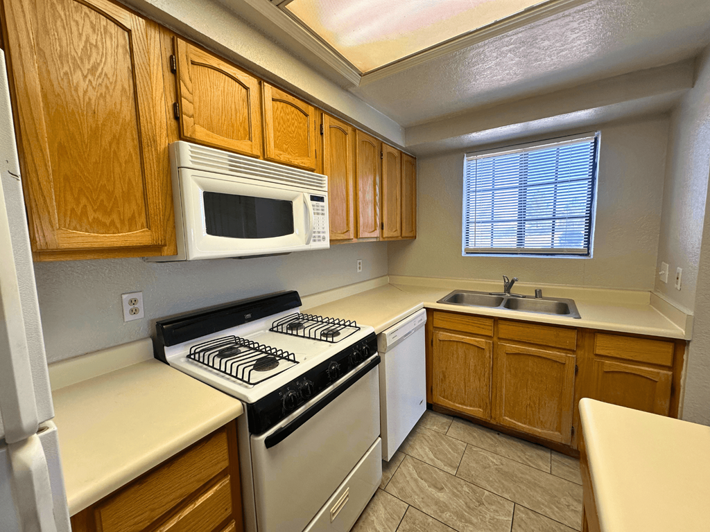 A kitchen with wooden cabinets and a white microwave.