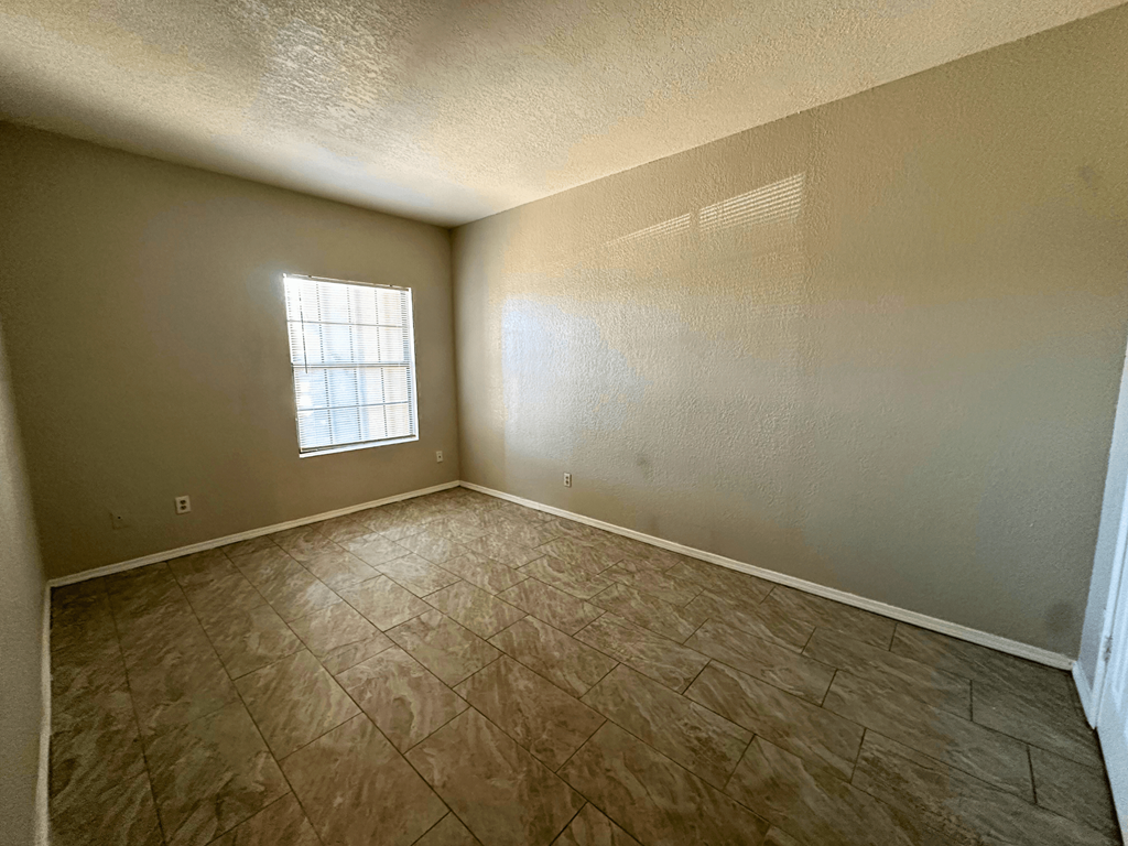 A room with a window and tile flooring.