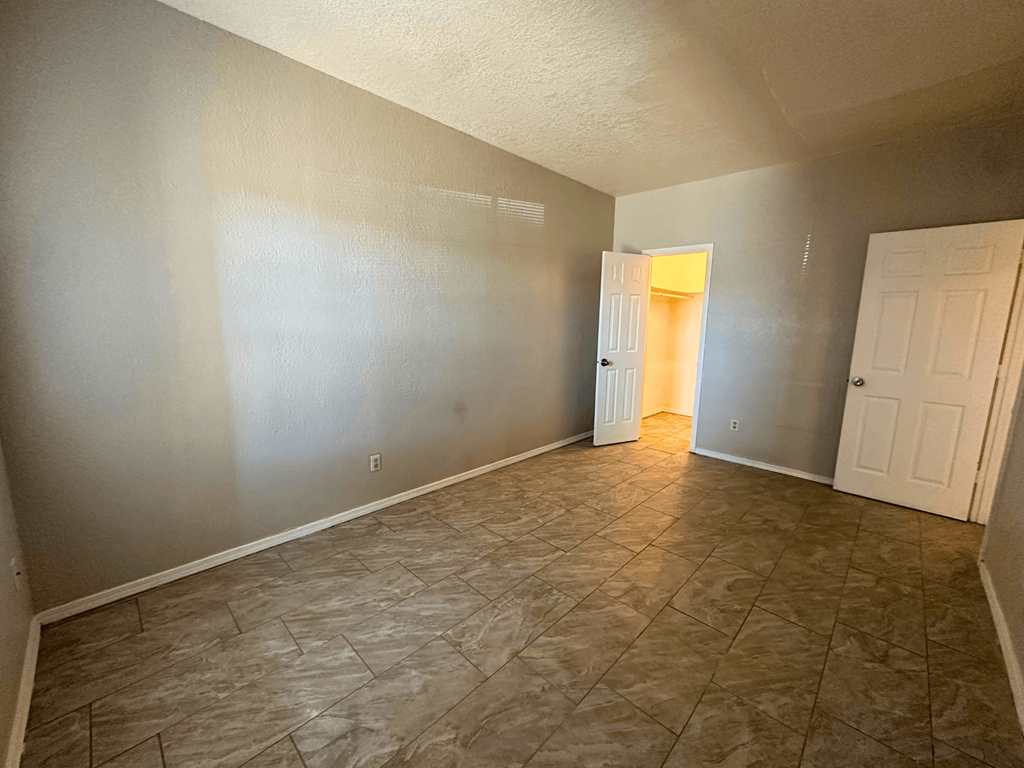 A room with tile flooring and a doorway leading to another room.