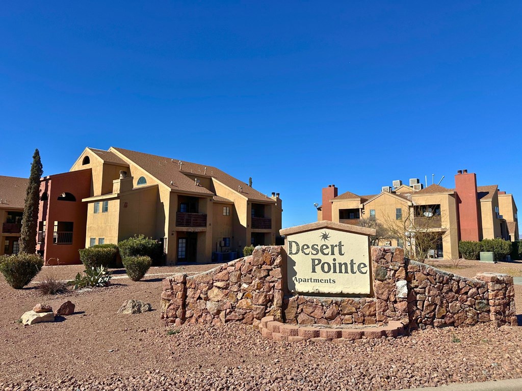 A sign that says Desert Pointe Apartments in front of some buildings.