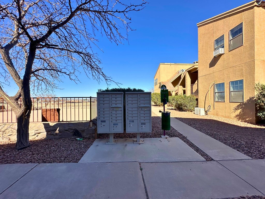 A tree is in front of a building and a sign is on the ground.