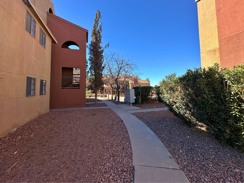A building with a red door and a small courtyard with a gravel path.