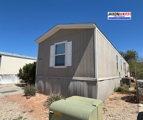 A small house with a grey and white exterior and a green utility box in front.