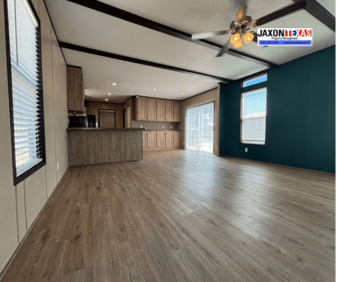 A spacious room with wooden flooring and a ceiling fan.