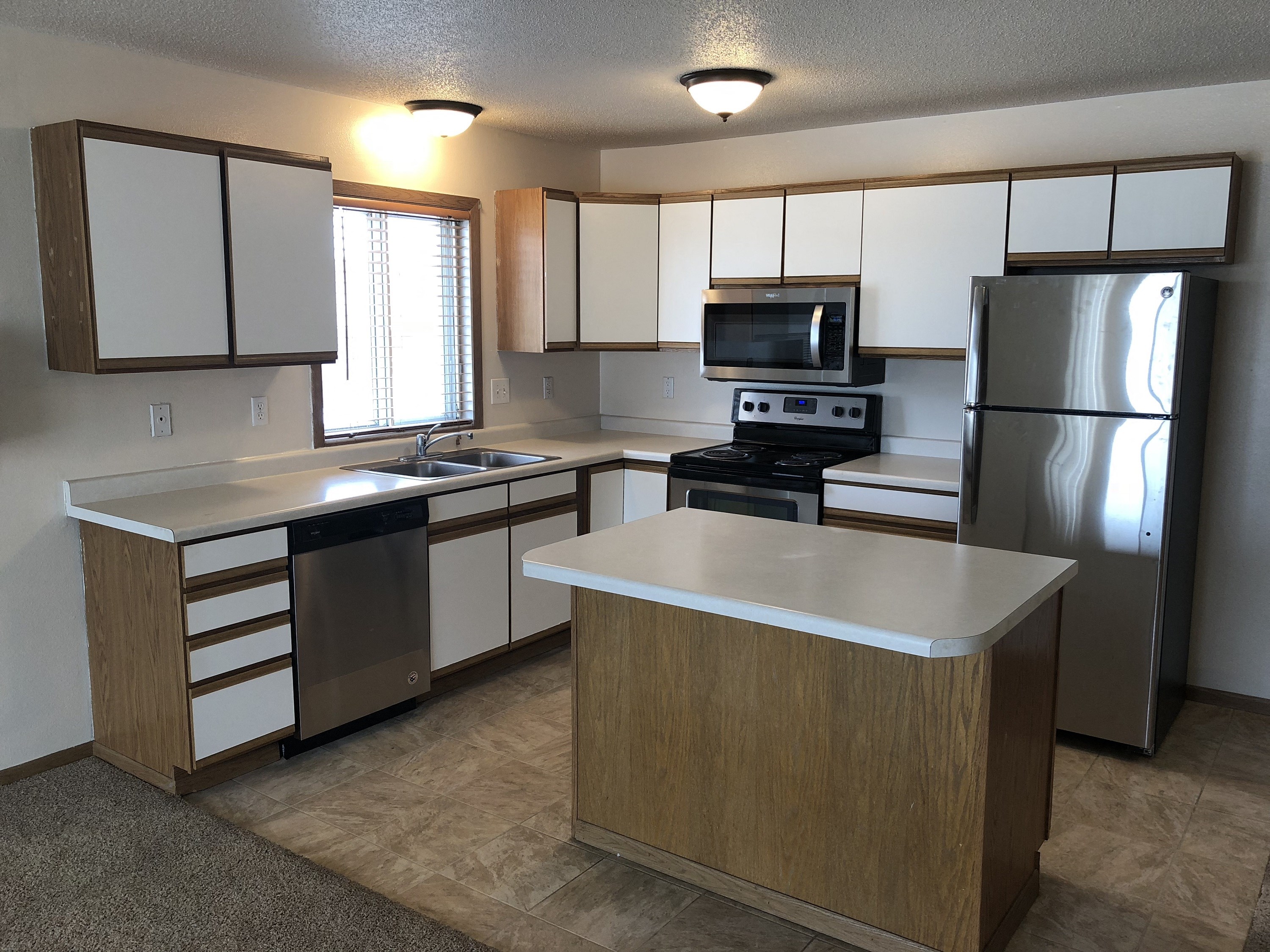 an empty kitchen with stainless steel appliances and white cabinets