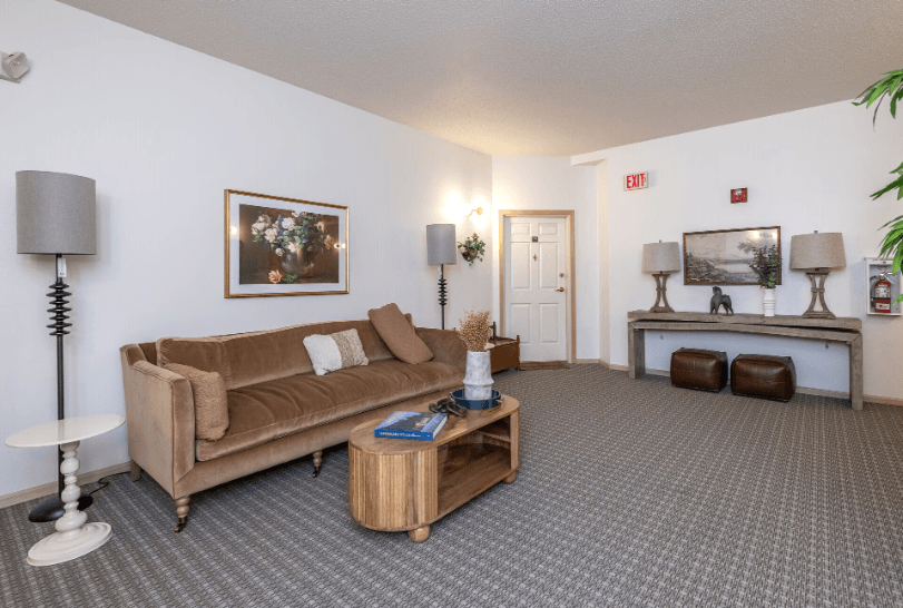 A living room with a brown couch, a coffee table, and a lamp at Eighth Street Manor Apartments, North Dakota, 58103