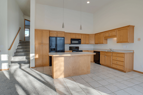 A kitchen with wooden cabinets and a black fridge.