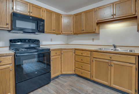 A kitchen with wooden cabinets and a black oven.