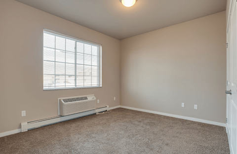 A room with a window and a wall-mounted air conditioner.