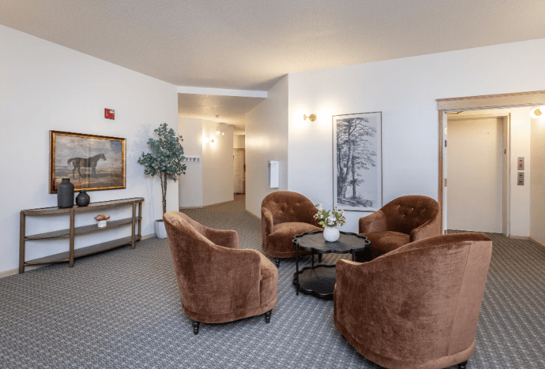 A room with brown chairs and a painting of a horse on the wall at Eighth Street Manor  Apartments, Fargo, ND