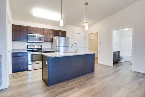 an empty kitchen with a large island and stainless steel appliances
