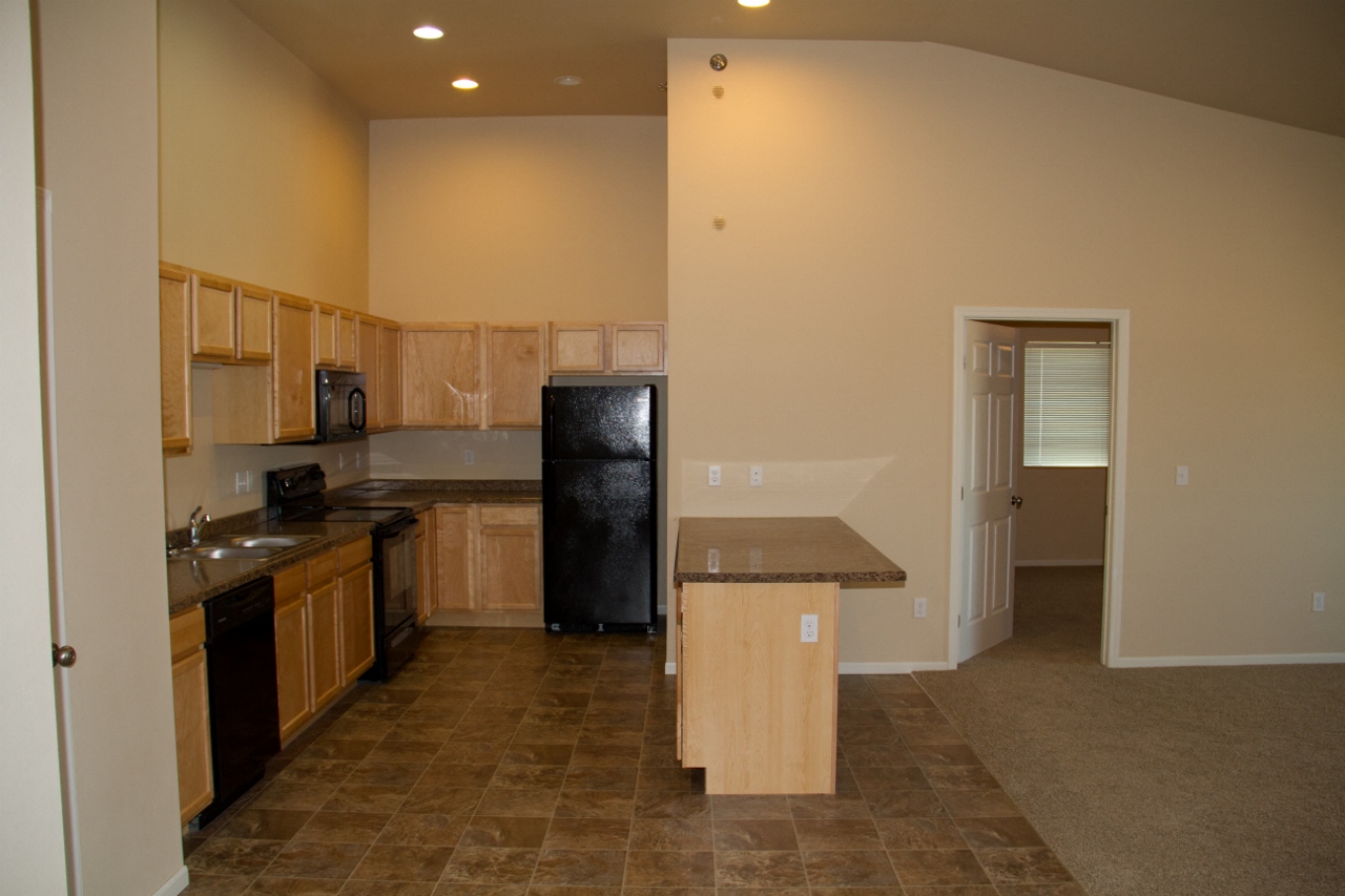 a kitchen with wooden cabinets and a black refrigerator