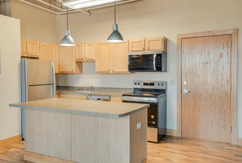 A kitchen with wooden cabinets and a stainless steel refrigerator, Kassenborg Apartments, Moorhead, MN