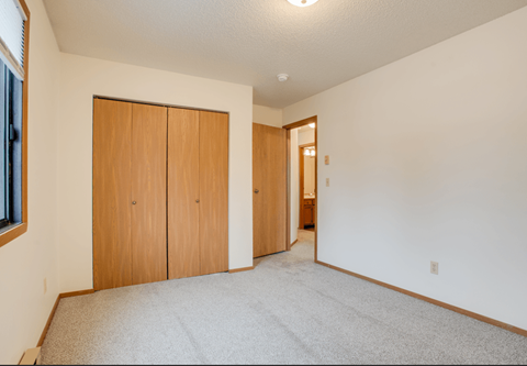 A room with a carpeted floor and two wooden doors.