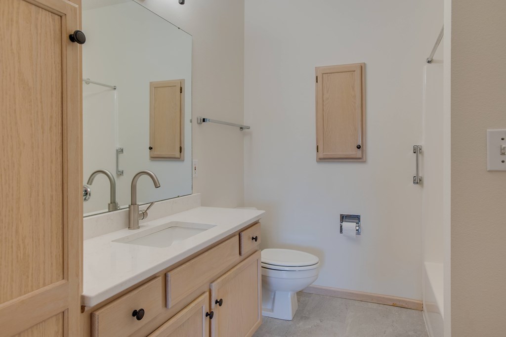 A bathroom with a sink, toilet and mirror. at Eighth Street Manor Apartments, Fargo, 58103