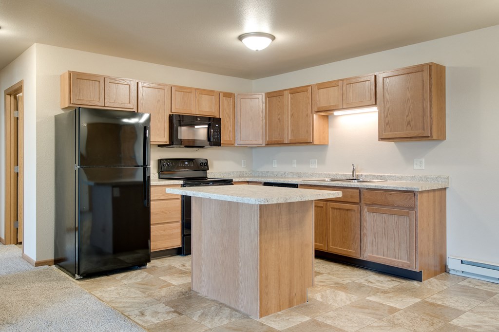 a kitchen with wooden cabinets and a black refrigerator