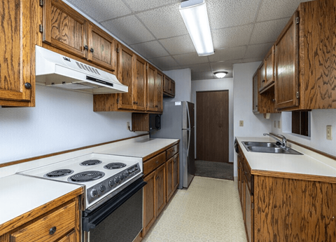 A kitchen with wooden cabinets and a stove top oven.