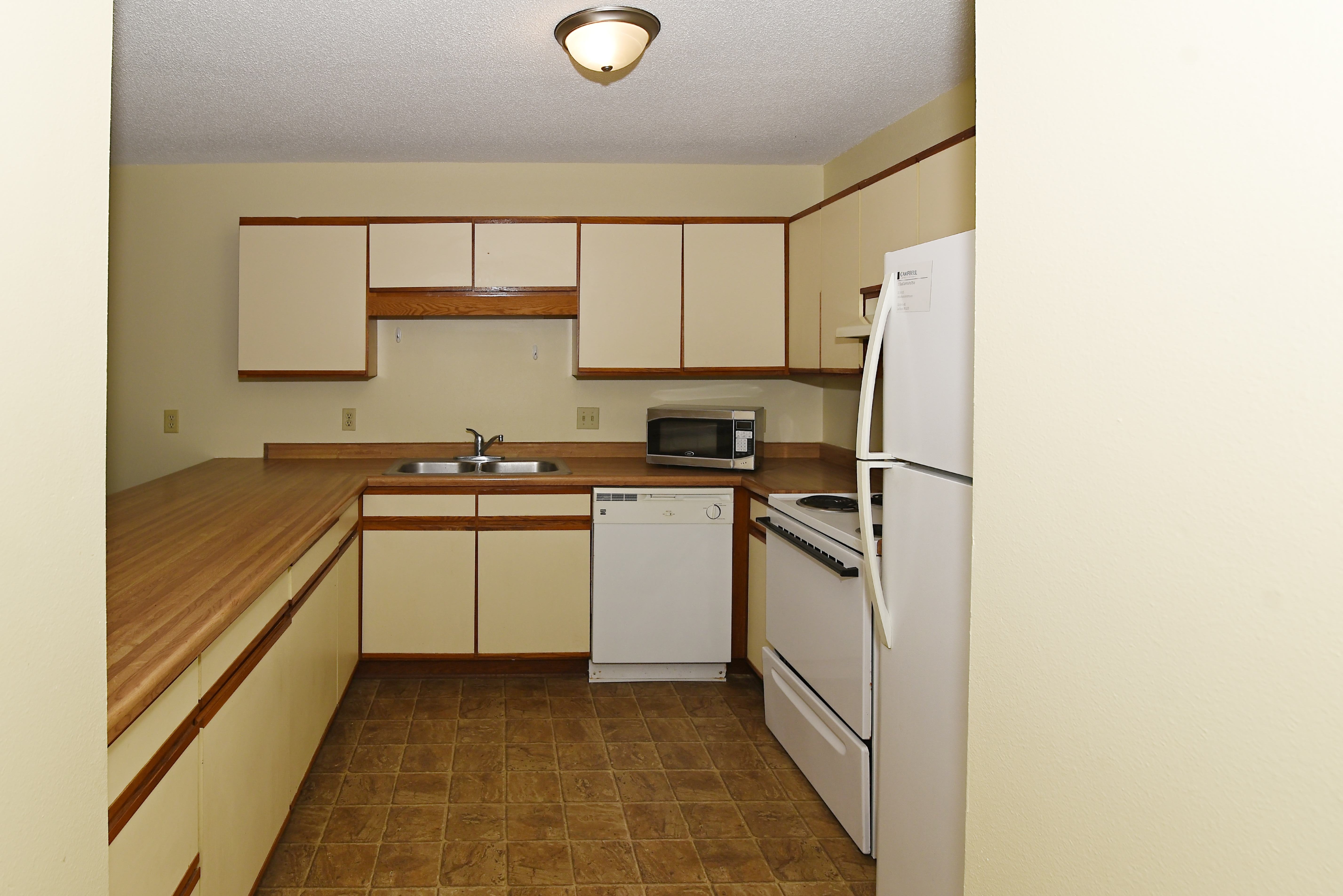 an empty kitchen with white appliances and a wooden counter top