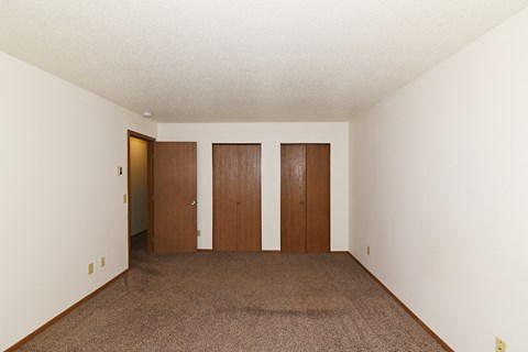 an empty room with carpet and white walls and wooden doors