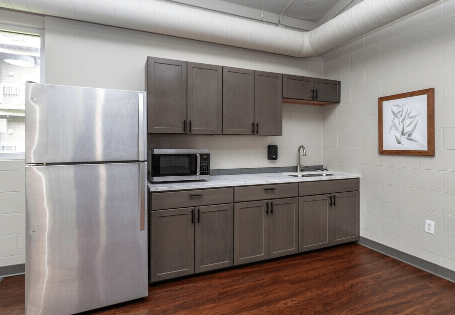 A kitchen with a stainless steel refrigerator and wooden floors at Courtyard Apartments on Belsly Apartments, Moorhead, Minnesota