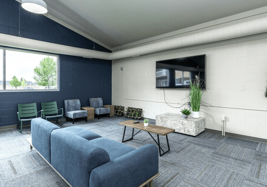 A room with blue couches and a television mounted on the wall at Courtyard Apartments on Belsly Apartments, Moorhead, MN, 56560