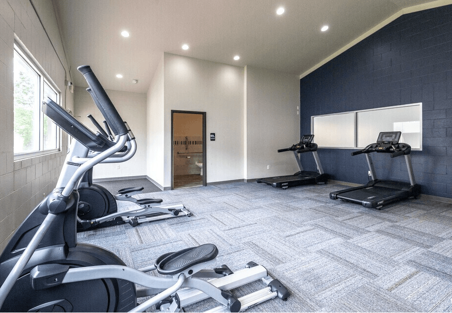 A gym with treadmills, elliptical machines, and a stationary bike at Courtyard Apartments on Belsly Apartments, Moorhead, 56560