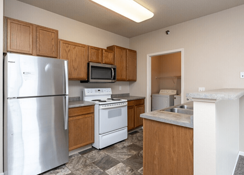 A kitchen with a refrigerator, microwave, oven, and sink.