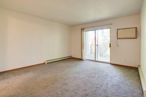 an empty living room with a sliding glass door to a patio