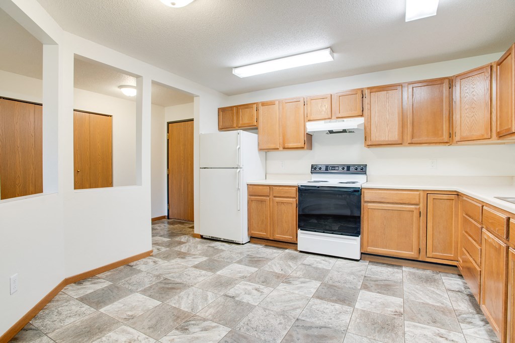 an empty kitchen with wood cabinets and white appliances