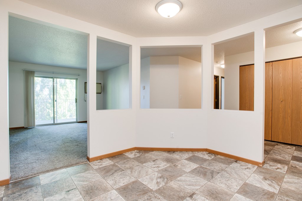 an empty living room with white walls and tile flooring