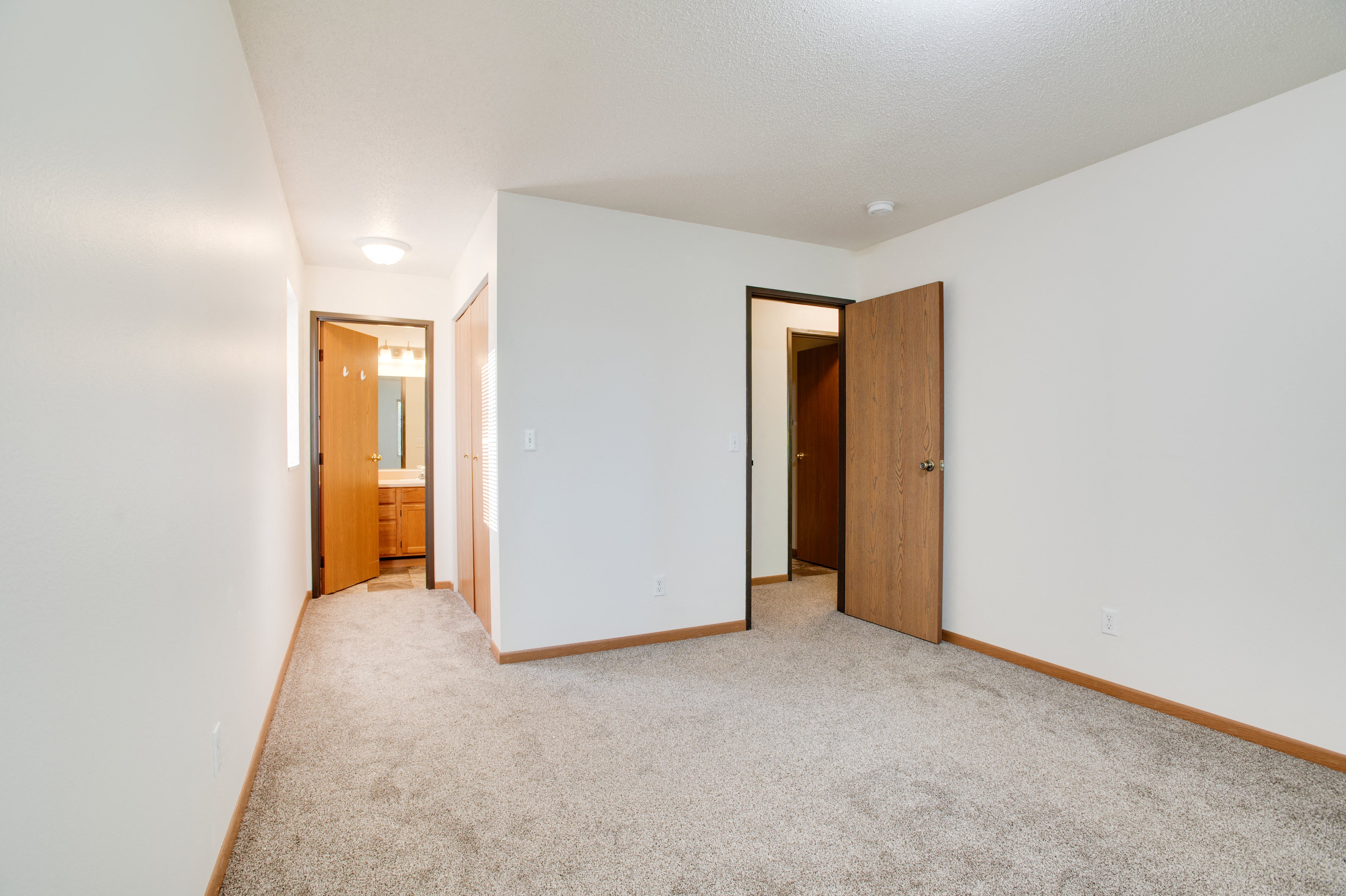 a bedroom with a carpeted floor and a door to a bathroom