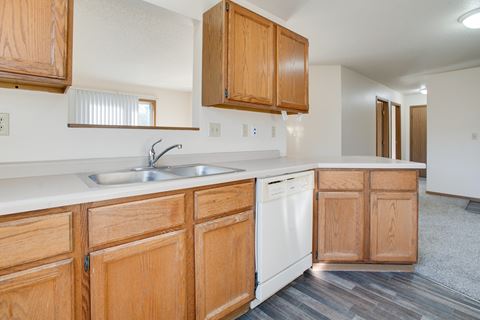 a kitchen with wooden cabinets and a white dishwasher and sink