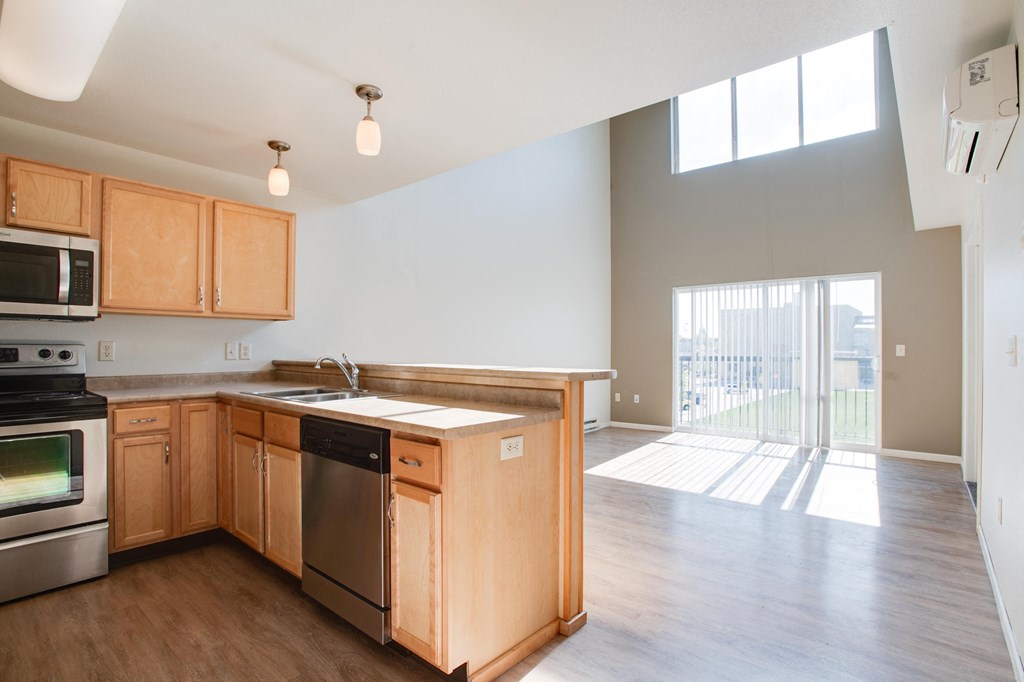 an empty kitchen with wooden cabinets and stainless steel appliances and a balcony at Urban Crossing Apartments, North Dakota, 58103