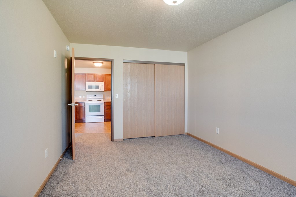 an empty living room with a door to a kitchen