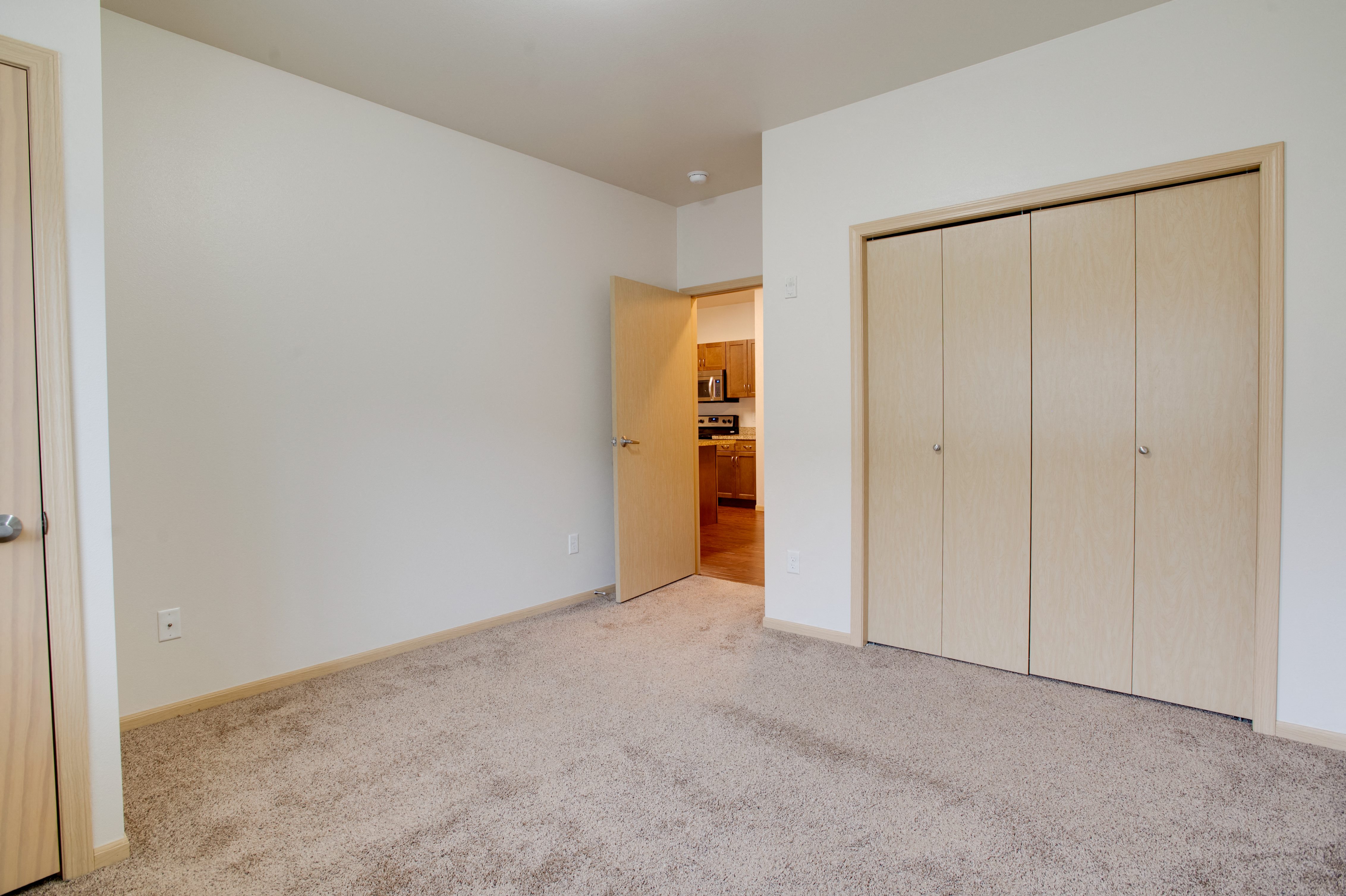 a bedroom with a closet and a door to a kitchen
