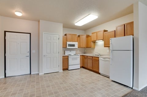 a kitchen with white appliances and wooden cabinets at Courtyard Apartments on Belsly, Moorhead, Minnesota