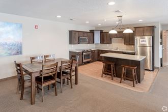 a dining area with a wooden table and chairs and a kitchen with stainless steel appliances at Paraiso Estates, Sauk Rapids, Minnesota