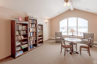 a room with a table and chairs and a bookshelf with books at Paraiso Estates, Sauk Rapids, Minnesota
