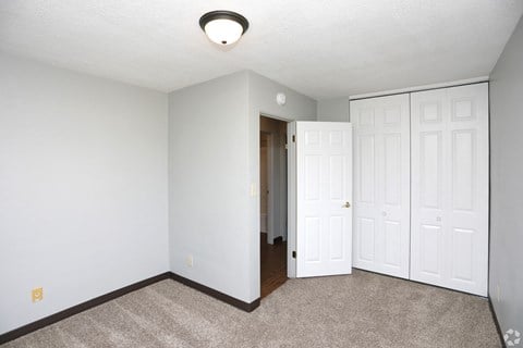 a bedroom with two closets and a carpeted floor at Southern Manor Apartments, North Dakota