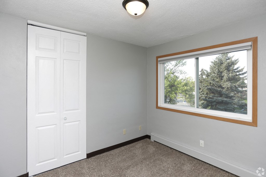a bedroom with a large window and a white door a bedroom with a large window and a white door at Southern Manor Apartments, Grand Forks, ND