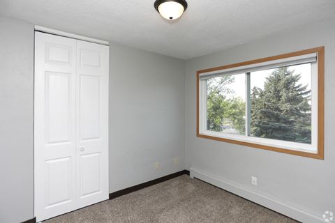 a bedroom with a large window and a white door at Southern Manor Apartments, Grand Forks, ND