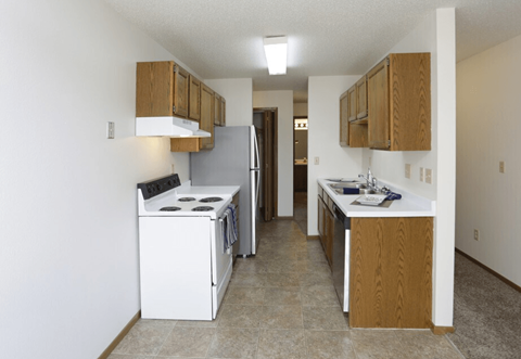 A kitchen with white appliances and wooden cabinets.