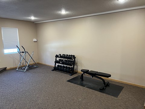 a small exercise room with weights and a bench at Bluemont Village Apartments, Fargo, ND, 58103