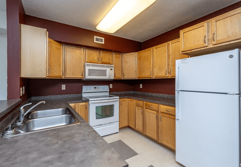A kitchen with wooden cabinets and a white refrigerator.