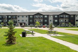 a picnic area with two picnic tables in front of an apartment building