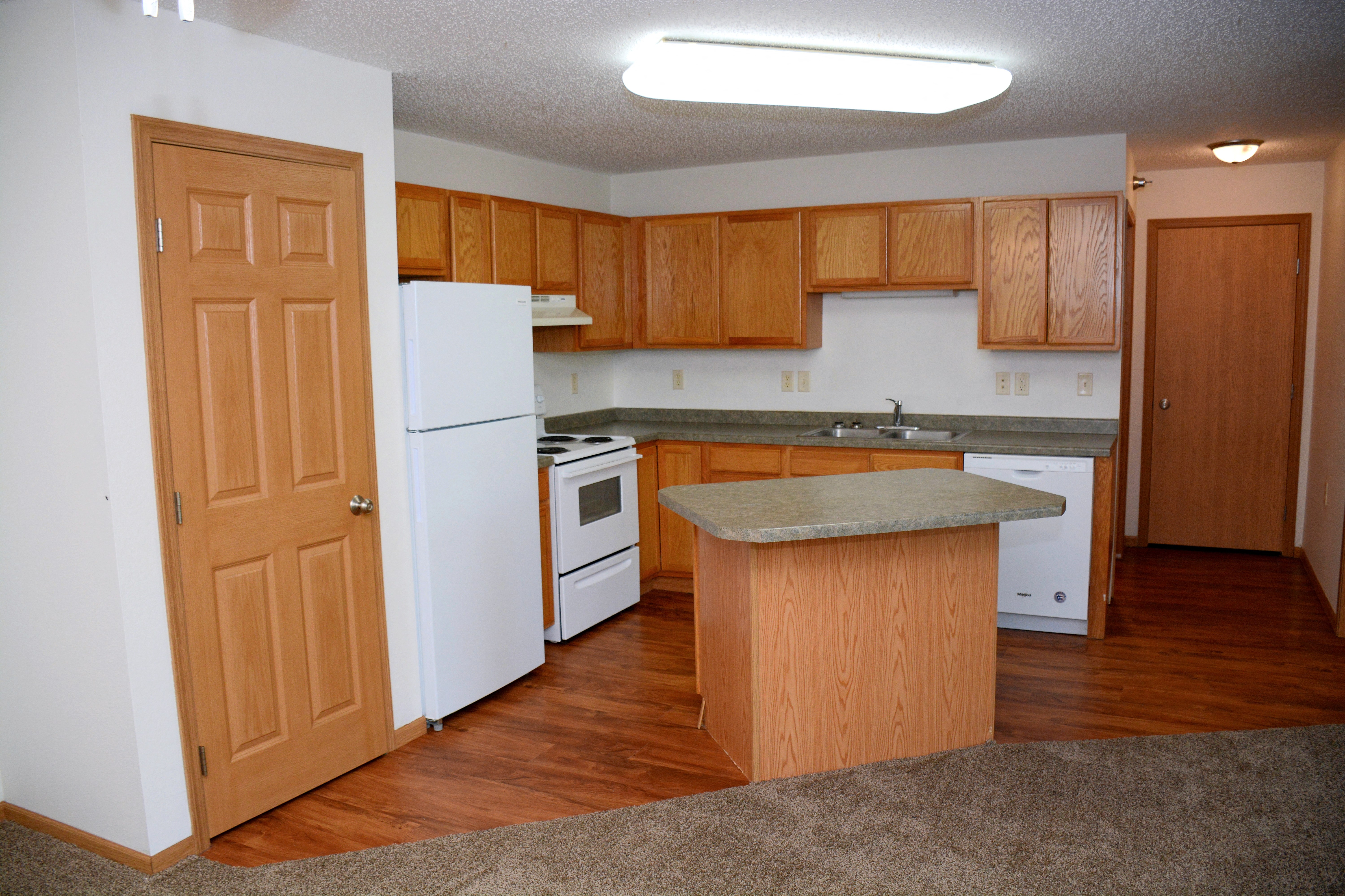 an empty kitchen with wooden cabinets and white appliances